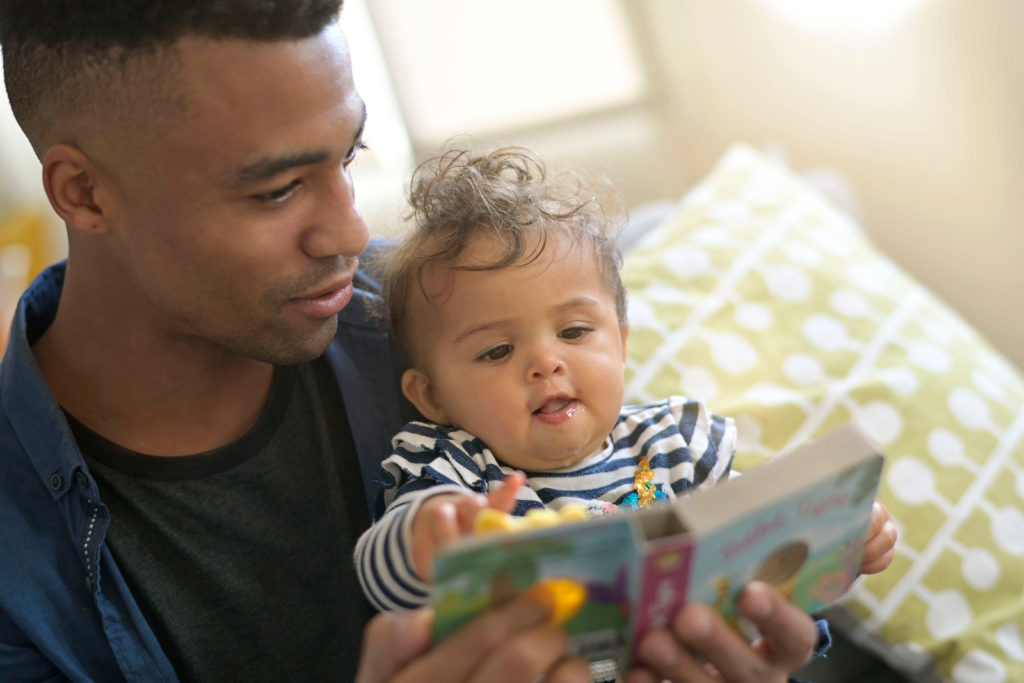 young african-american man reading book story to baby girl